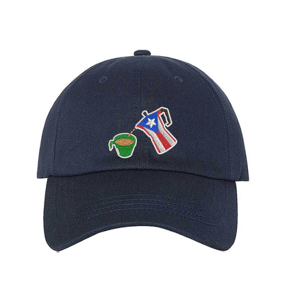 A navy embroidered hat featuring a detailed design of a greca (stovetop coffee maker) pouring coffee into a nostalgic green butter cup, symbolizing Puerto Rican coffee culture. The greca has the Puerto Rican flag inside it, representing heritage and tradition. DSY Lifestyle