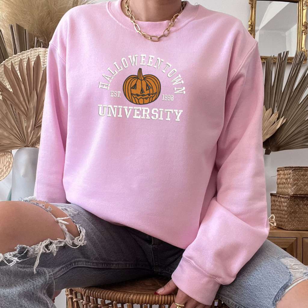 Female wearing a Light Pink sweatshirt embroidered with Halloweentown University Est. 1998 and a pumpkin - DSY Lifestyle