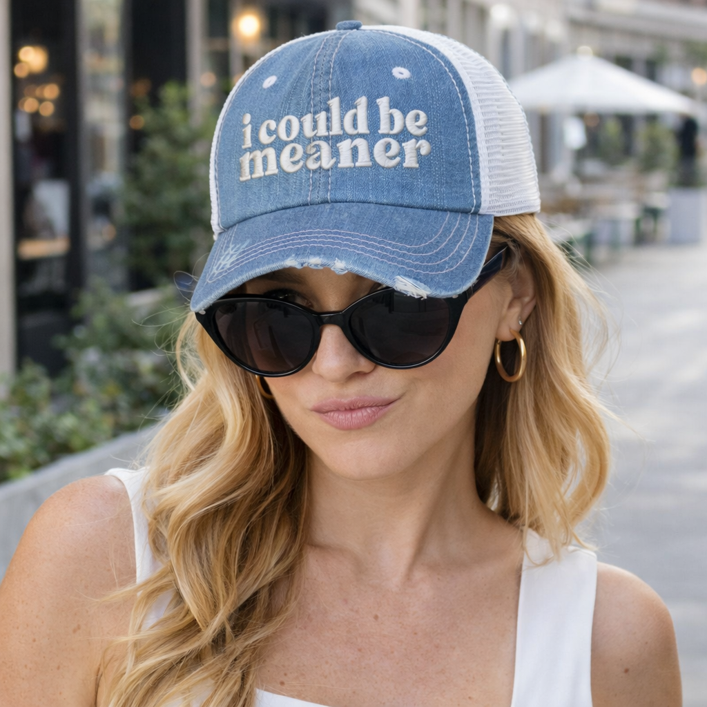 A detailed view of female with confident look wearing a Denim DSY Lifestyle distressed trucker hat featuring the phrase I Could Be Meaner in bold, professional embroidery. - DSY Lifestyle