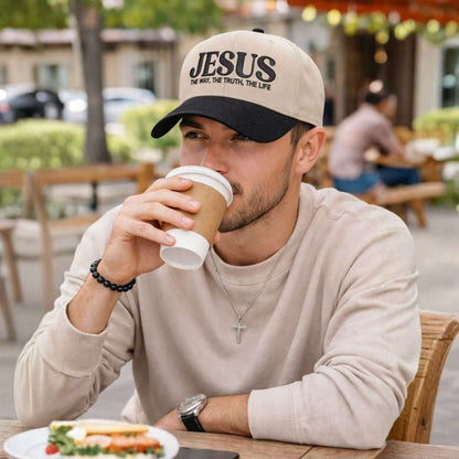 Handsome male sipping coffee outside of the coffee shop wearing Natural Black Jesus The Way The Truth The Life 3D Two-Tone Hat featuring bold 3D raised embroidery on a natural crown with a contrasting visor; a premium faith statement by DSY Lifestyle.