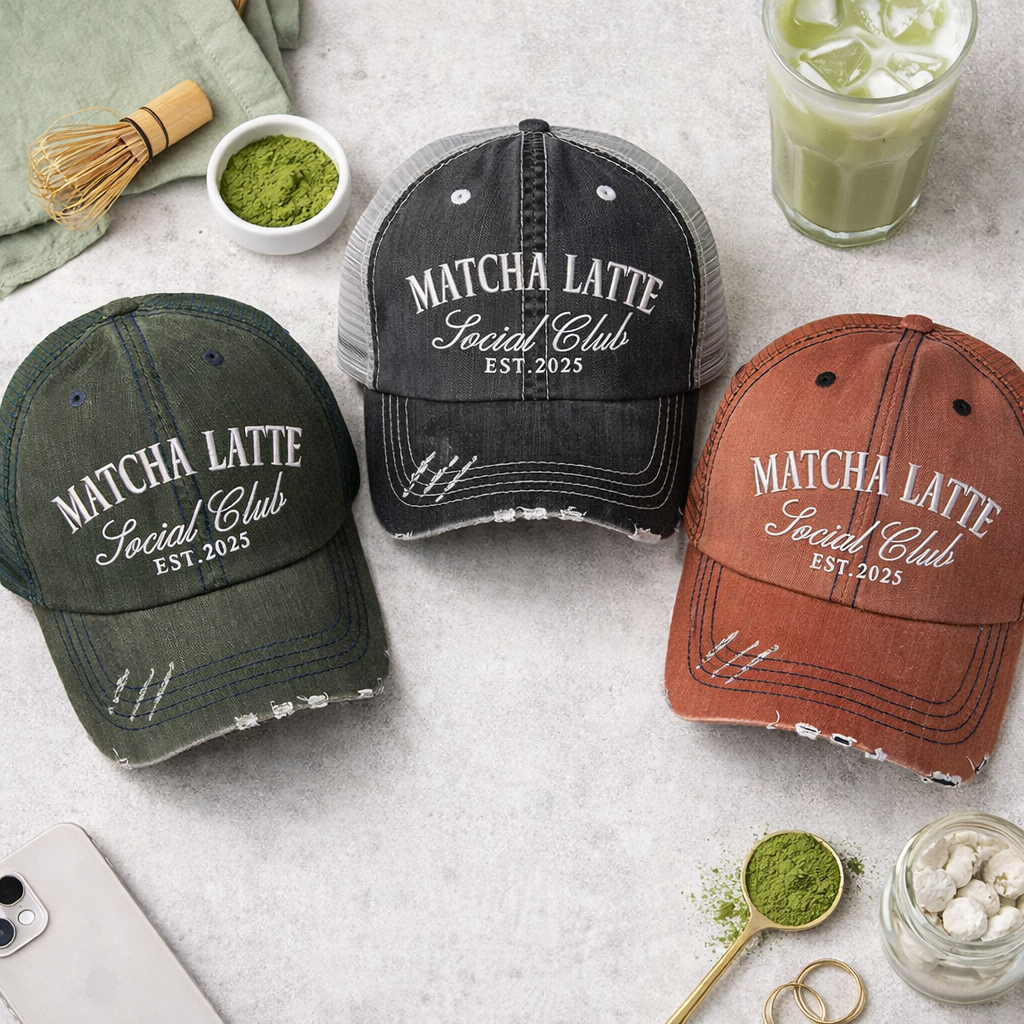 A flat lay view of a DSY Lifestyle distressed trucker hats featuring the words Matcha Latte Social Club Est. 2025 in detailed white embroidery. - DSY Lifestyle