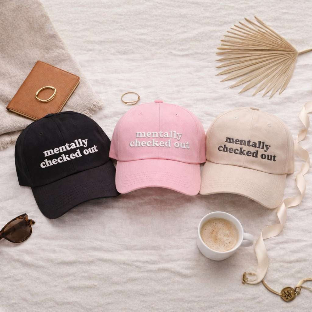 Flat lay of cotton baseball hats with the phrase Mentally Checked Out embroidered in a clean, modern font. - DSY Lifestyle