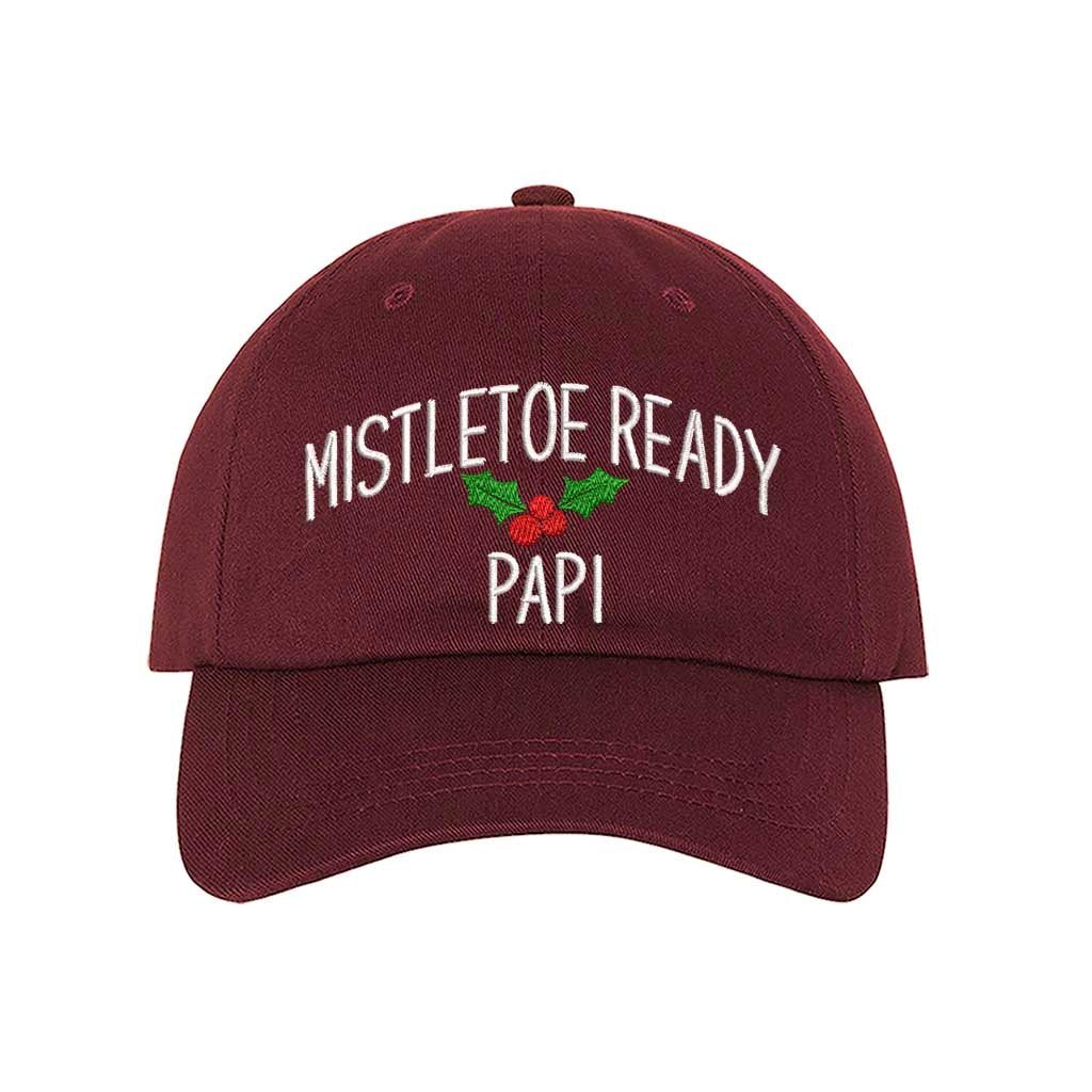 A festive burgundy baseball hat embroidered with Mistletoe Ready Papi and mistletoe, perfect for holiday parties and Spanglish Christmas vibes. DSY Lifestyle