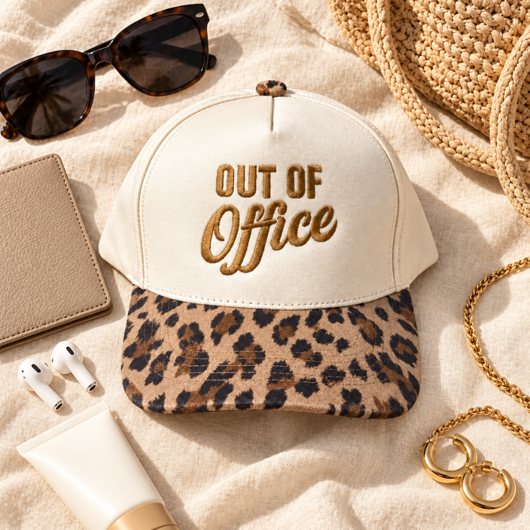A structured baseball cap with an off-white crown and a leopard-print visor, embroidered with &