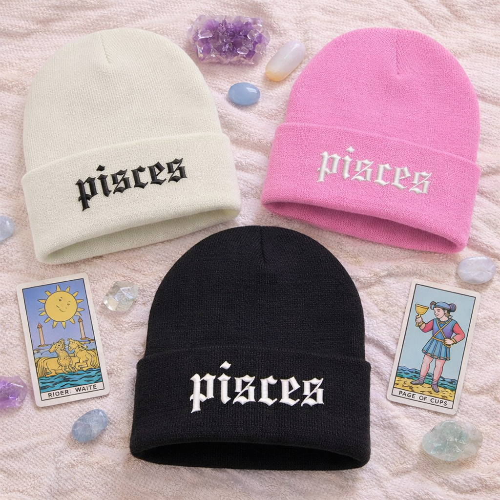 Three beanie hats embroidered with pisces text on a textured surface with tarot cards and crystals - DSY Lifestyle