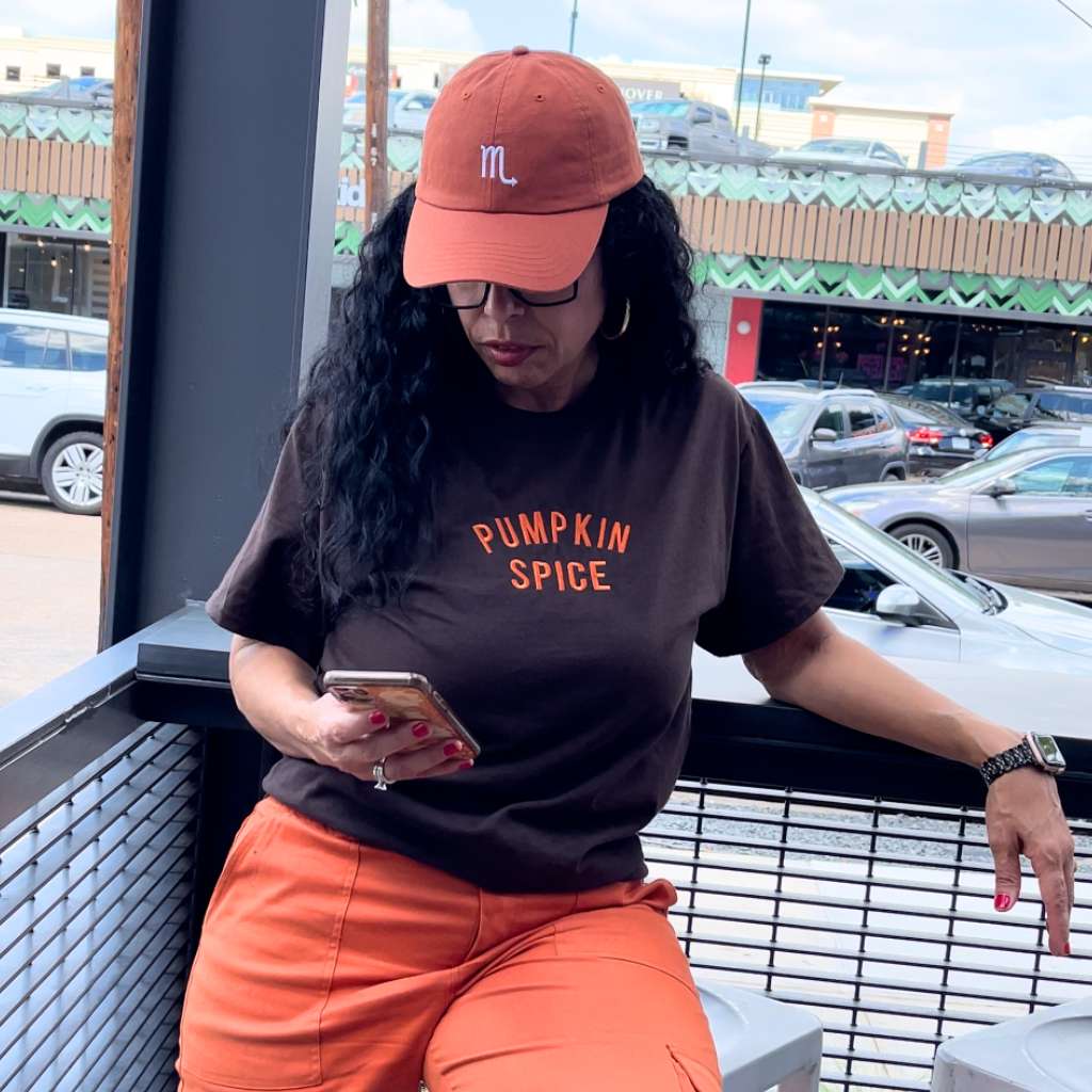 Female wearing a tshirt embroidered with Pumpkin Spice and a burnt orange baseball hat embroidered with Scorpio Zodiac Sign - DSY Lifestyle
