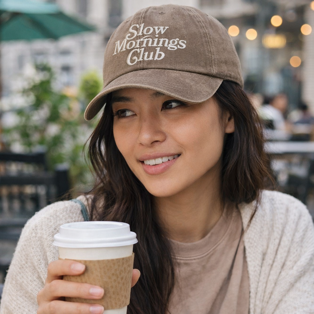 Female sitting outside cafe with coffee in hand wearing a Chocolate Brown Slow Mornings Club washed cotton baseball hat with a soft, lived-in finish and premium high-density embroidery by DSY Lifestyle. - DSY Lifestyle