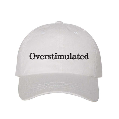 White DSY Lifestyle soft cotton baseball hat with the word Overstimulated embroidered in clean, minimalist lowercase lettering across the front. - DSY Lifestyle