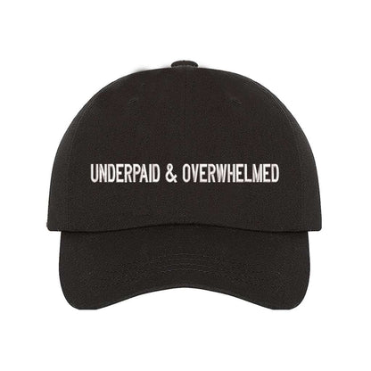 Black baseball hat with the phrase underpaid &amp; overwhelmed embroidered on it-DSY Lifestyle