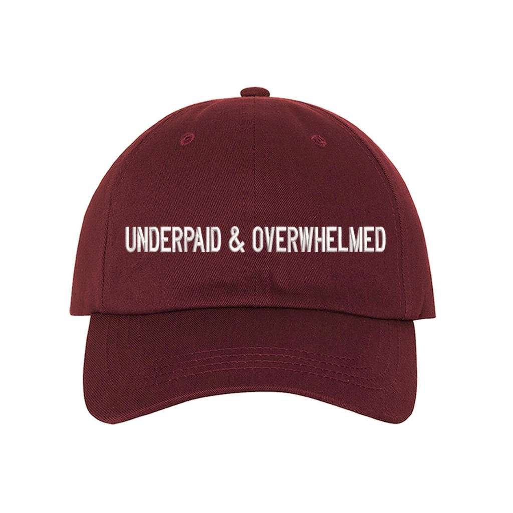 Burgundy baseball hat with the phrase underpaid &amp; overwhelmed embroidered on it-DSY Lifestyle