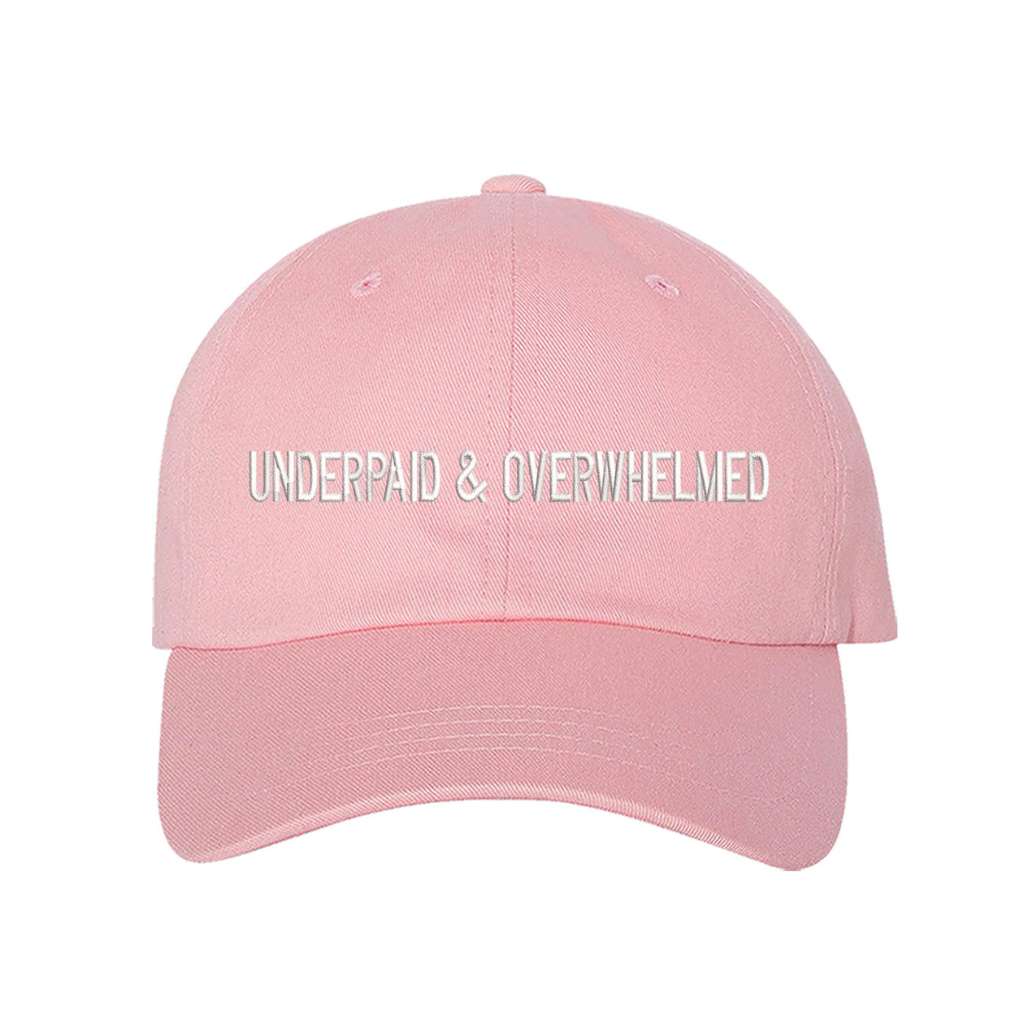 Light pink baseball hat with the phrase underpaid &amp; overwhelmed embroidered on it-DSY Lifestyle