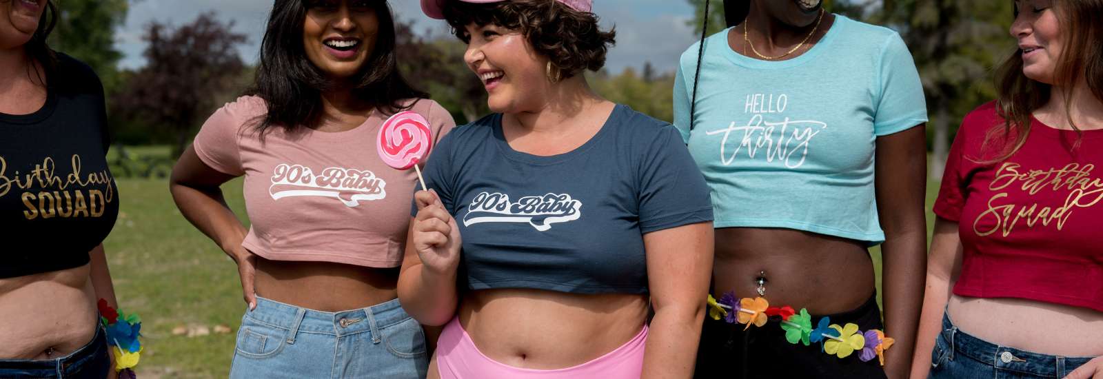 Women wearing underboob crop tops printed with 90's baby, Hello Thirty and Birthday Squad