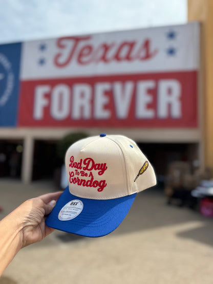 Side view of the Natural / Royal Blue Bill Bad Day To Be A Corndog hat showing the embroidered corndog on the side panel