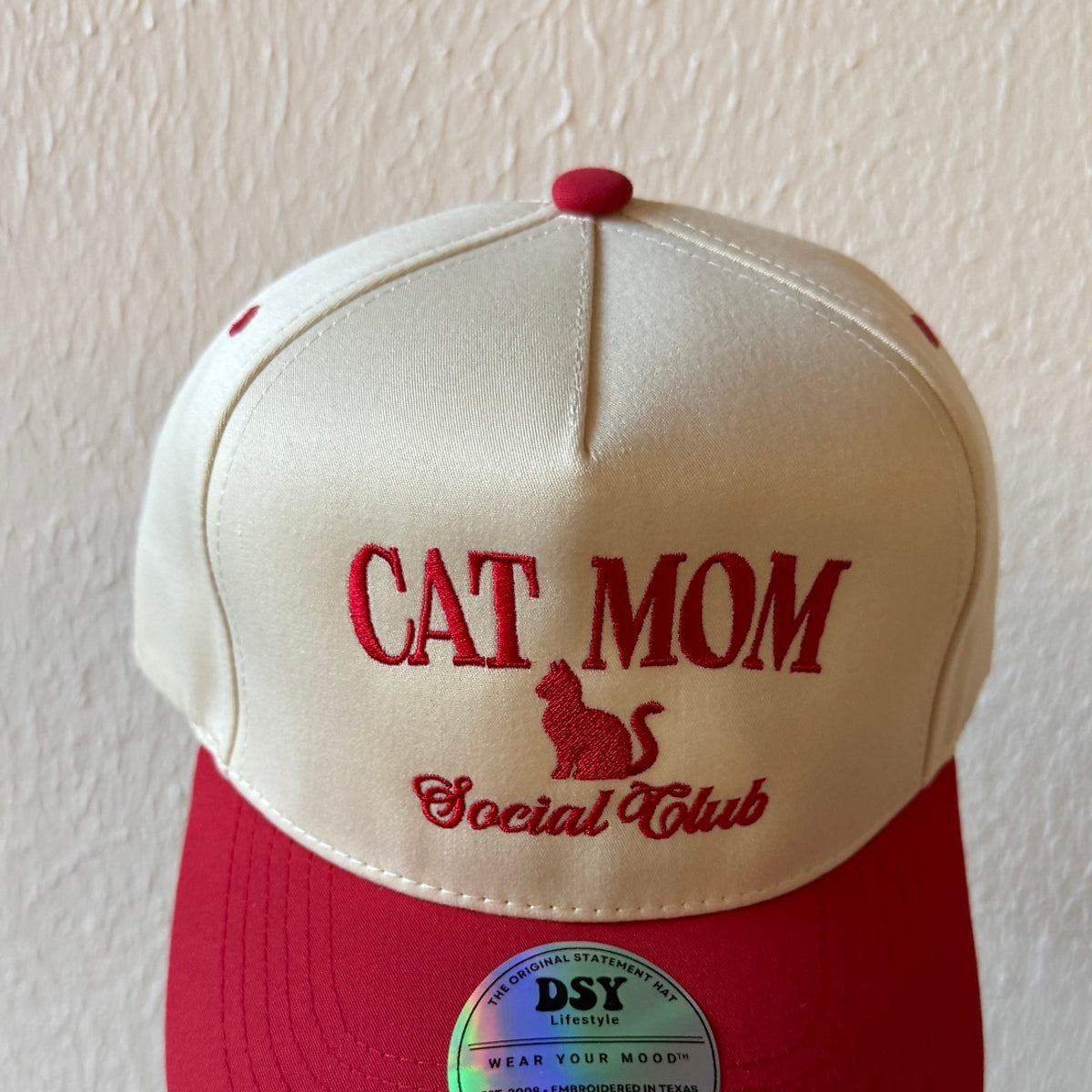 Close-up of Cat Mom Social Club machine embroidery on a two-tone trucker hat