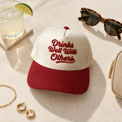 Drinks Well With Others two-tone embroidered trucker hat styled flat lay