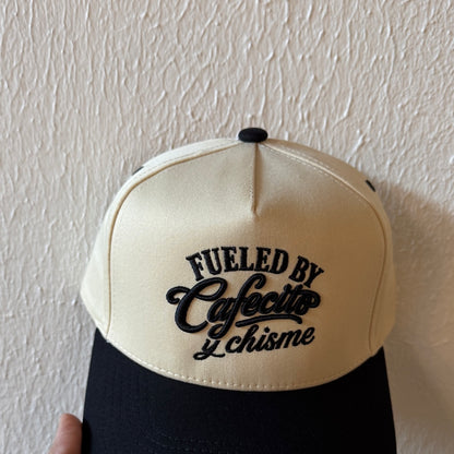 Close-up of Fueled by Cafecito y Chisme machine embroidery on a two-tone trucker hat