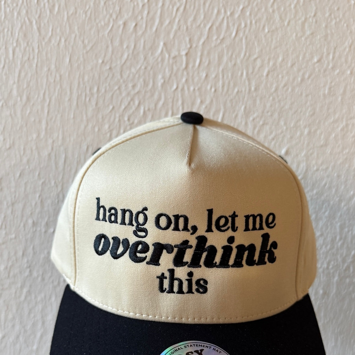 Close-up of Hang On, Let Me Overthink This machine embroidery on a two-tone trucker hat