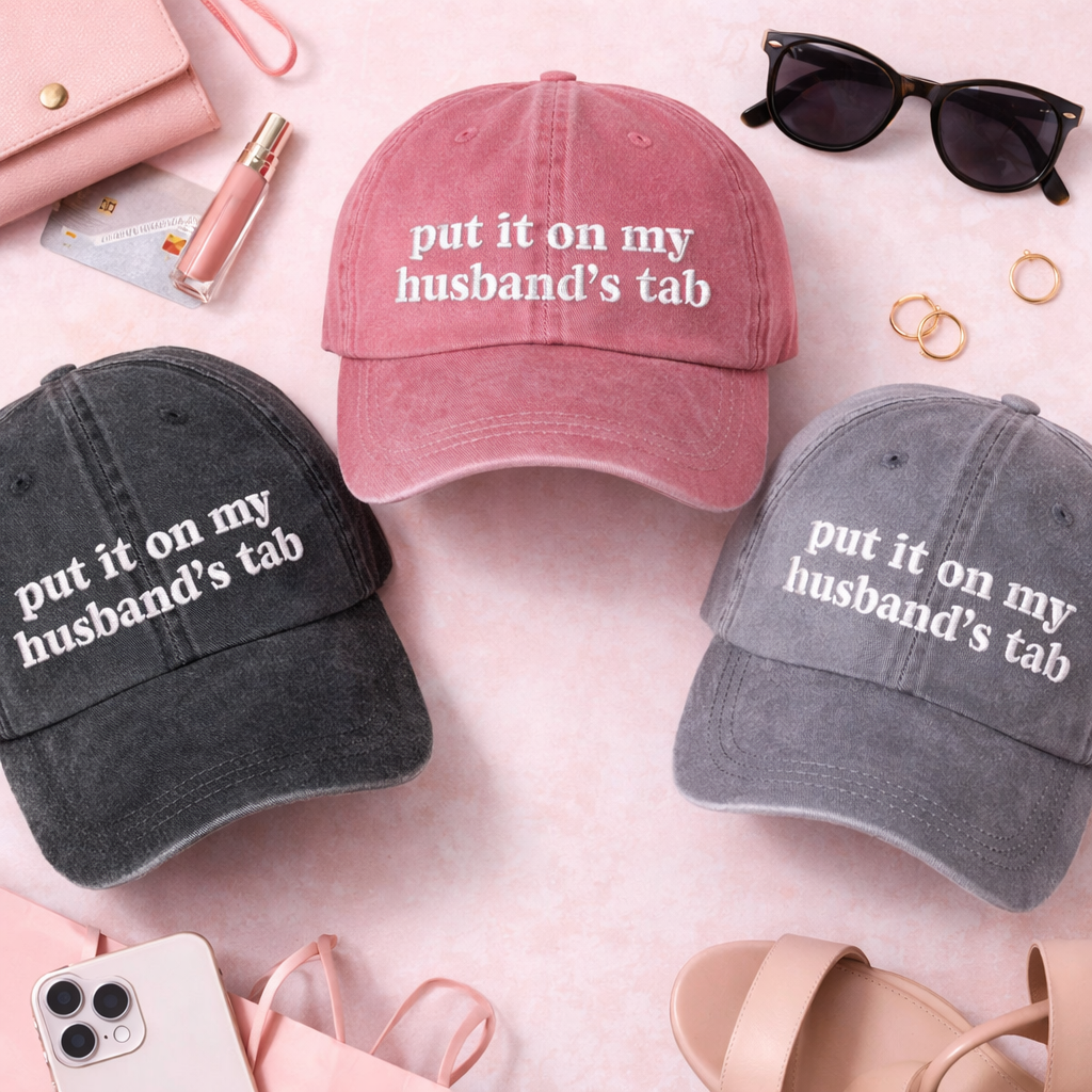 Flat lay on pink backdrop of Black, Wine, and Gray Put It On My Husband’s Tab washed cotton baseball hats with a soft finish and high-density white embroidery by DSY Lifestyle. - DSY Lifestyle