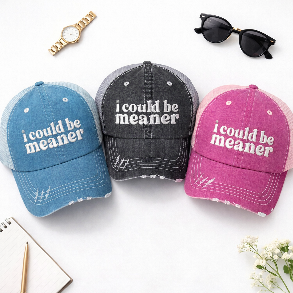 A detailed view of a flat lay of DSY Lifestyle distressed trucker hats featuring the phrase I Could Be Meaner in bold, professional embroidery. - DSY Lifestyle