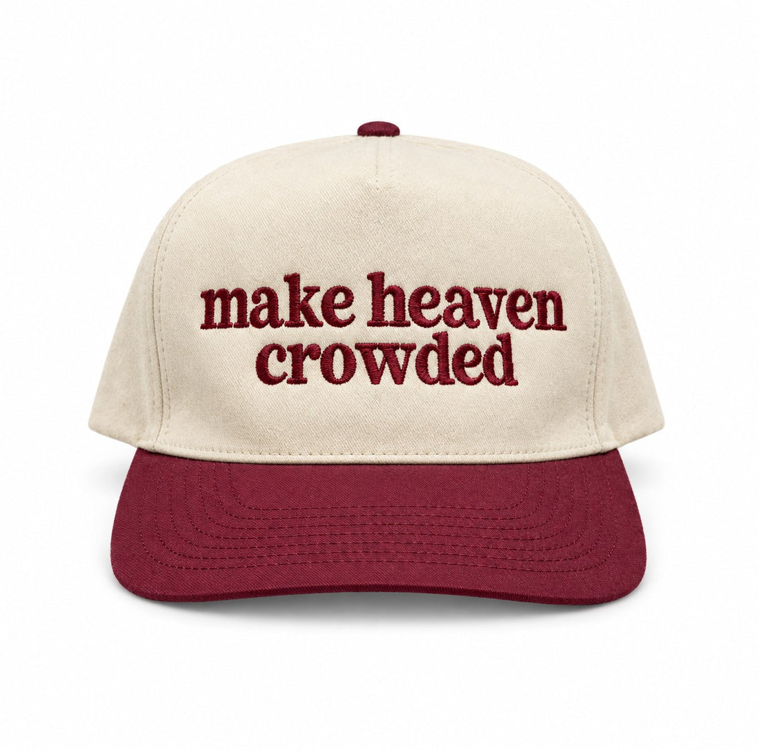 Make heaven crowded embroidered trucker hat with natural crown and maroon bill on a white background