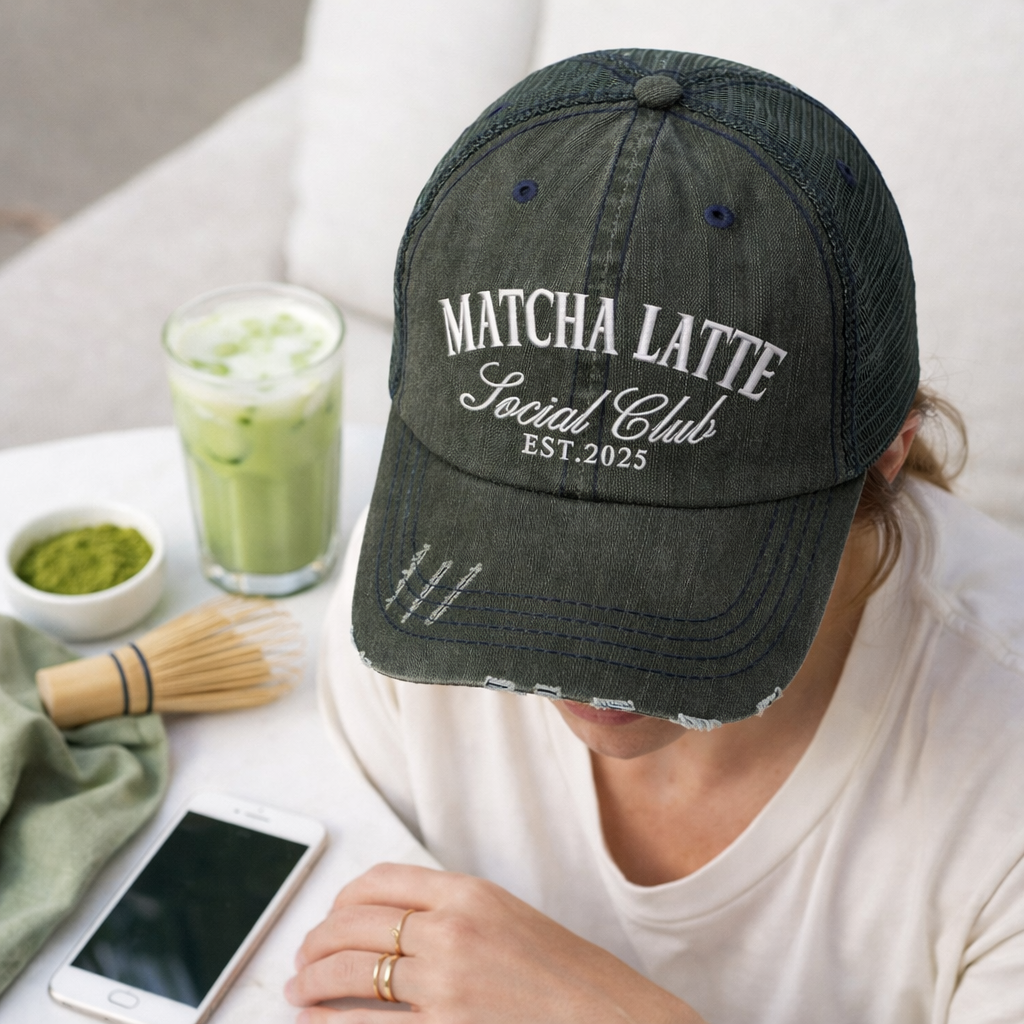 A front view of female wearing Black DSY Lifestyle distressed trucker hat featuring the words Matcha Latte Social Club Est. 2025 in detailed white embroidery. - DSY Lifestyle