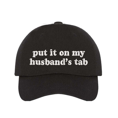 Black Put It on My Husband’s Tab Embroidered Baseball Hat in soft cotton with curved brim and adjustable back strap, perfect for vacations and girls’ nights. DSY Lifestyle.