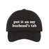 Black Put It on My Husband’s Tab Embroidered Baseball Hat in soft cotton with curved brim and adjustable back strap, perfect for vacations and girls’ nights. DSY Lifestyle.