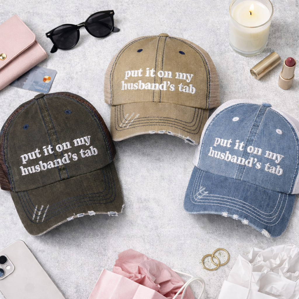 Flat lay of Black, Khaki, and Denim front DSY Lifestyle distressed trucker hats featuring the words Put It On My Husband&