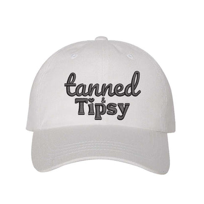 White Tanned and Tipsy Embroidered Baseball Hat in classic cotton with pre-curved brim and hook and loop closure, perfect for beach days and summer drinks. DSY Lifestyle.