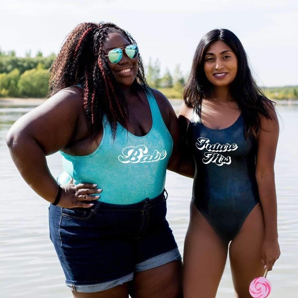 Two Females one wearing a Babe Aqua Glitter One Piece and the other one wearing a black glitter one piece with Future Mrs. printed in the front- DSY Lifestyle