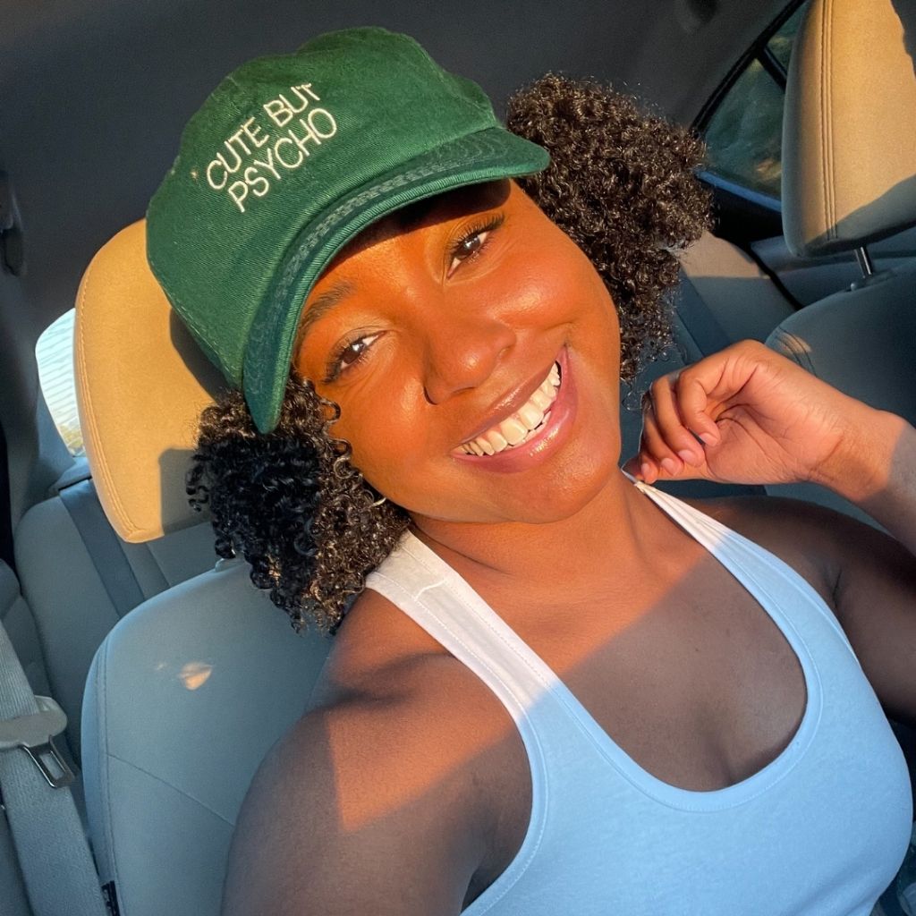 Chamique wearing a kelly green  embroidered cute but psycho baseball hat - DSY Lifestyle