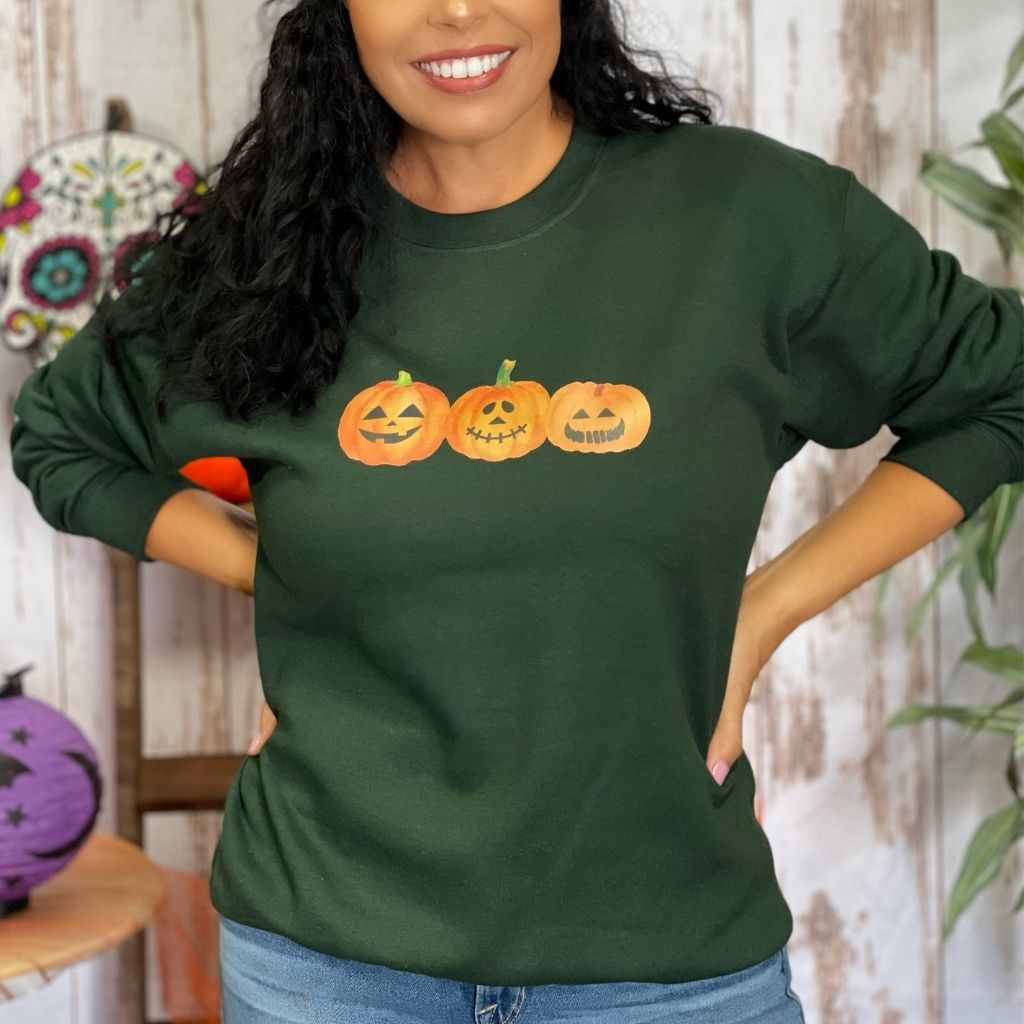 Female wearing a olive crewneck sweatshirt printed with 3 smiling pumpkins in the front - DSY Lifestyle