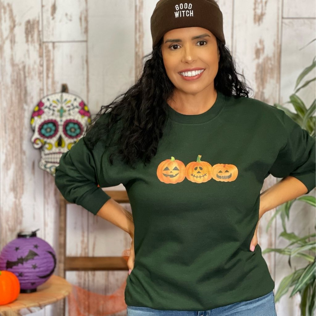 Female wearing a olive crewneck sweatshirt printed with 3 smiling pumpkins in the front - DSY Lifestyle