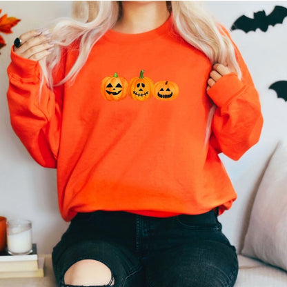 Female wearing a orange crewneck sweatshirt printed with 3 smiling pumpkins in the front - DSY Lifestyle