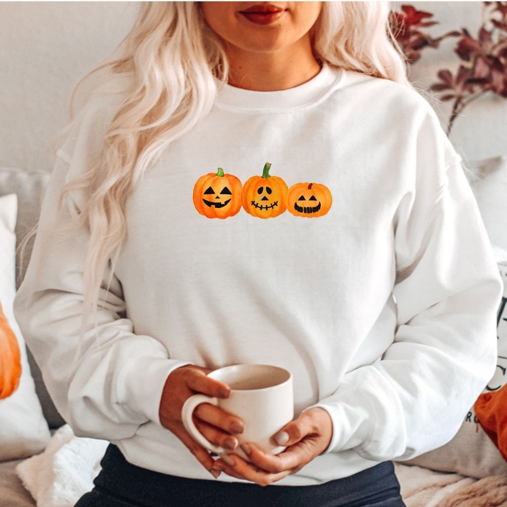 Female wearing a white crewneck sweatshirt printed with 3 smiling pumpkins in the front - DSY Lifestyle