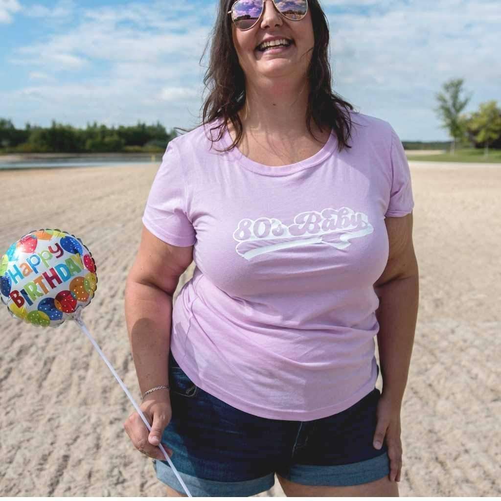 Female at a lake wearing a Lilac Unisex T-shirt with 80&