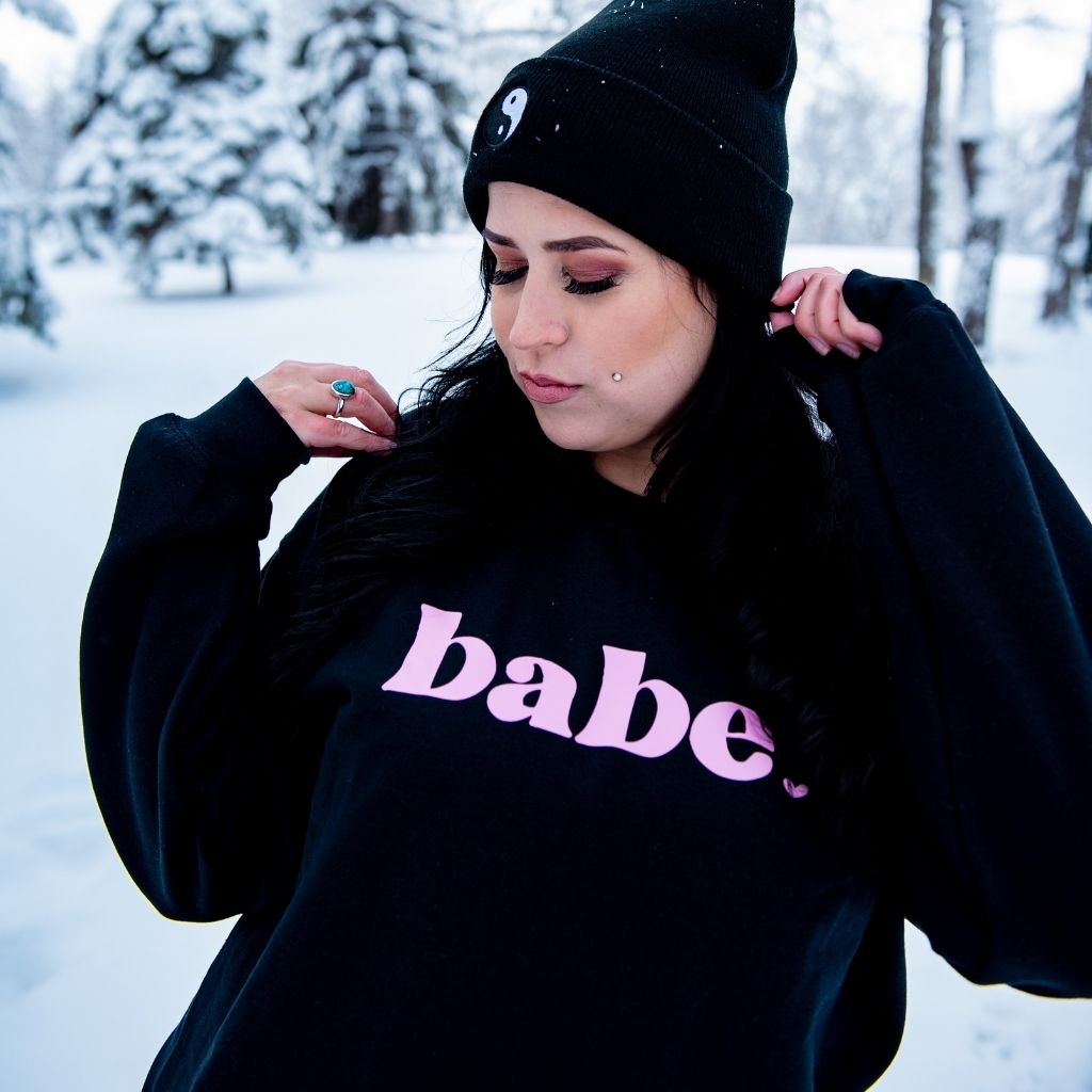 Female in the snow wearing a black sweatshirt with babe printed in pink - DSY Lifestyle