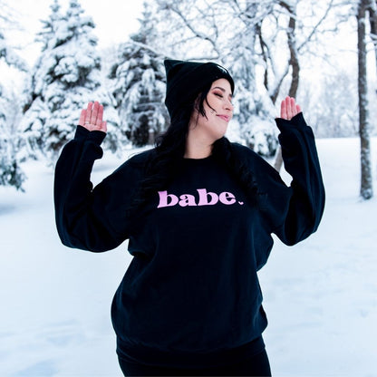 Female in the snow wearing a black sweatshirt with babe printed in pink - DSY Lifestyle