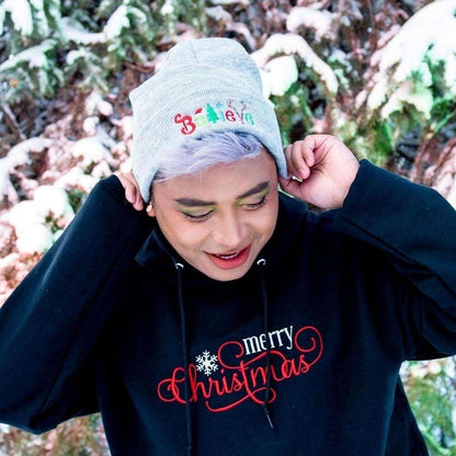 Model wearing light heather grey cuffed beanie with Believe embroidered with Christmas symbols - DSY Lifestyle