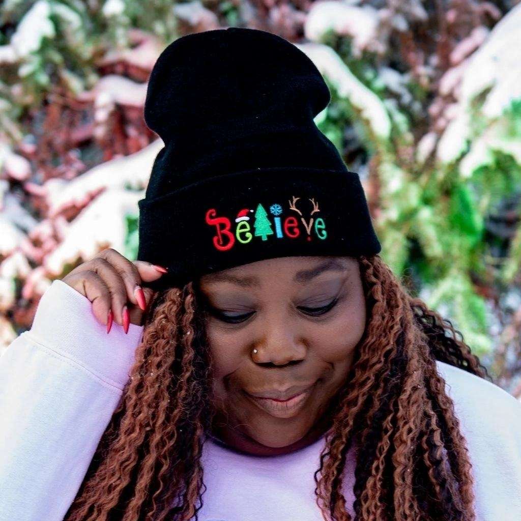 Model wearing black cuffed beanie with Believe embroidered with Christmas symbols - DSY Lifestyle