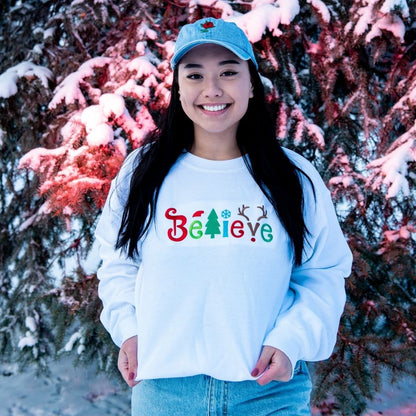 Female wearing white sweatshirt embroidered with believe in Christmas Colors- DSY Lifestyle