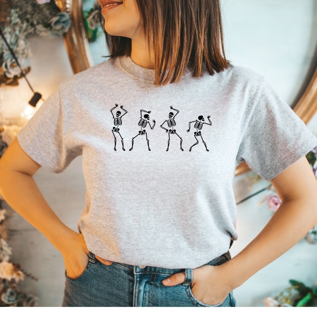 Female wearing a heather gray unisex t-shirt with printed white dancing skeletons in the front - DSY Lifestyle