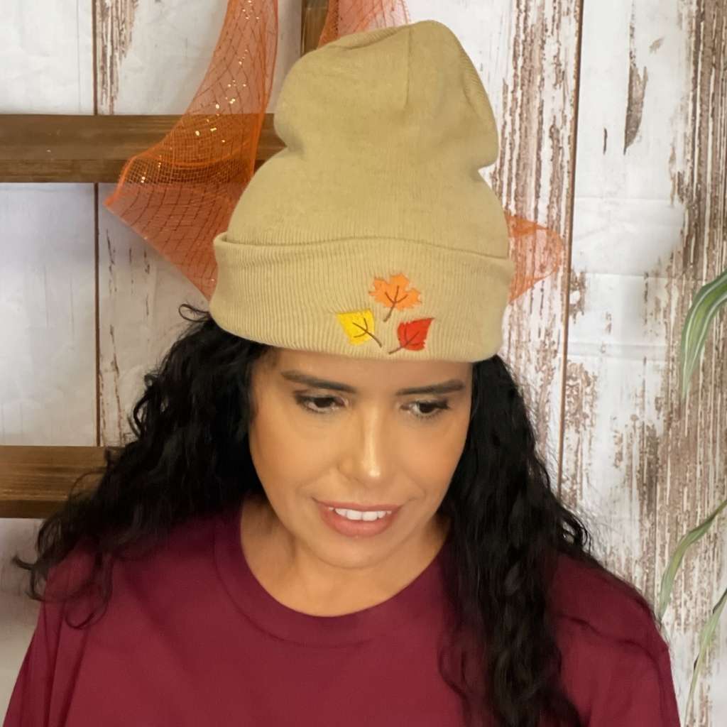 Model wearing tan cuffed beanie with orange, yellow, and red fall leaves embroidered on the front - DSY Lifestyle