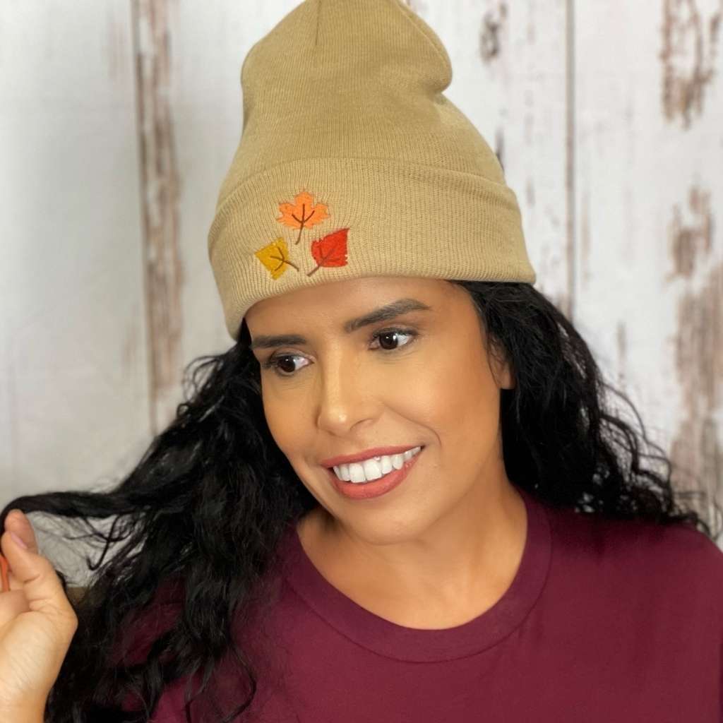 Model wearing tan cuffed beanie with orange, yellow, and red fall leaves embroidered on the front - DSY Lifestyle