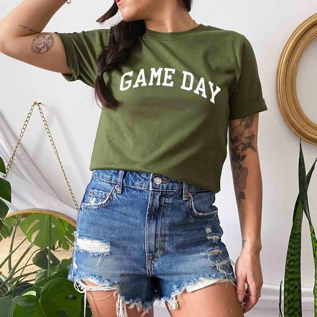 Female wearing a Olive  t-shirt printed with Game Day in white - DSY Lifestyle