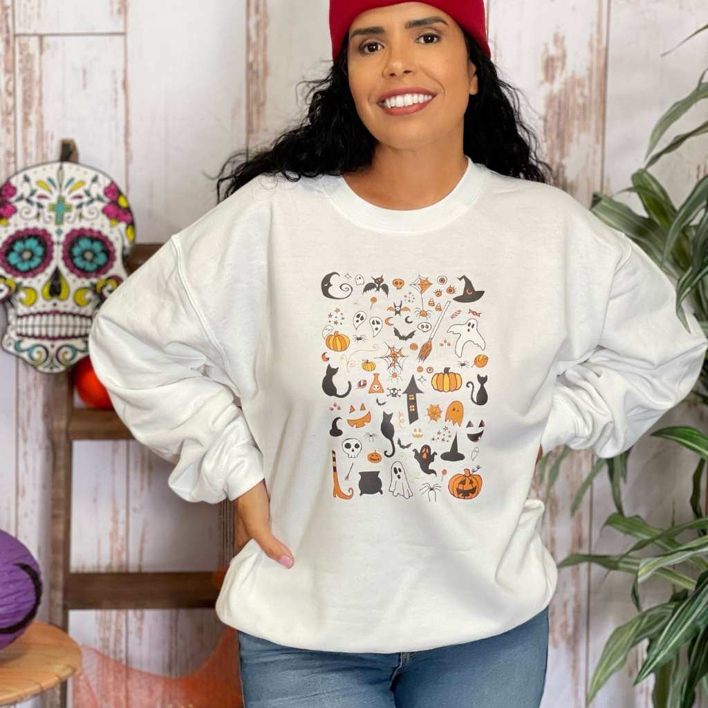 Woman wearing a over sized white  sweatshirt with halloween doodles printed on the front- DSY Lifestyle