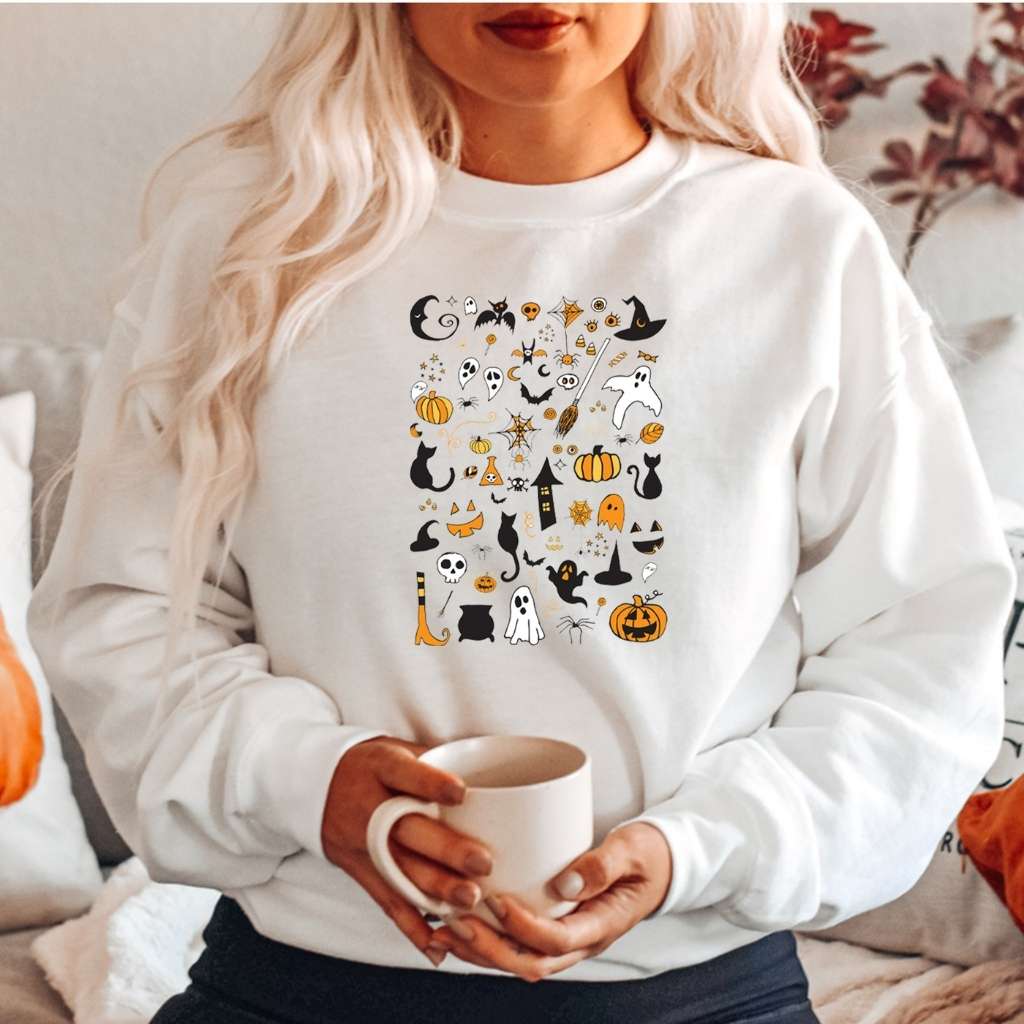 Woman wearing a over sized white sweatshirt with halloween doodles printed on the front- DSY Lifestyle