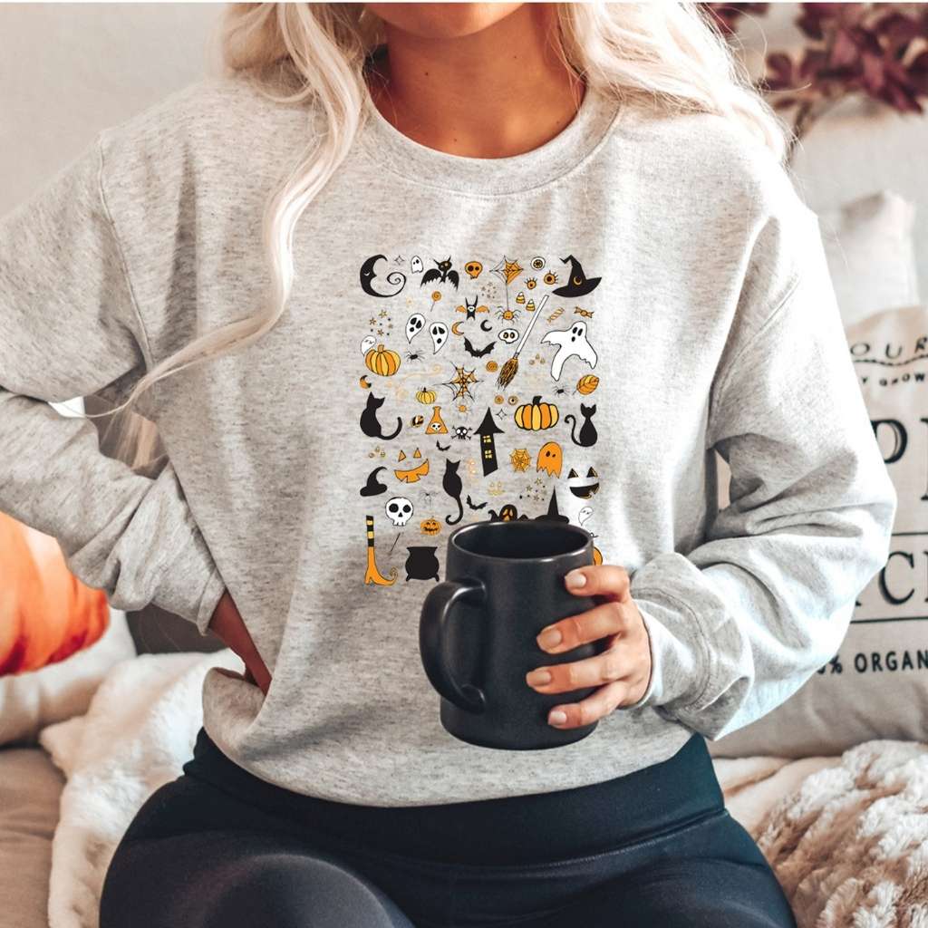 Woman wearing a over sized gray sweatshirt with halloween doodles printed on the front- DSY Lifestyle