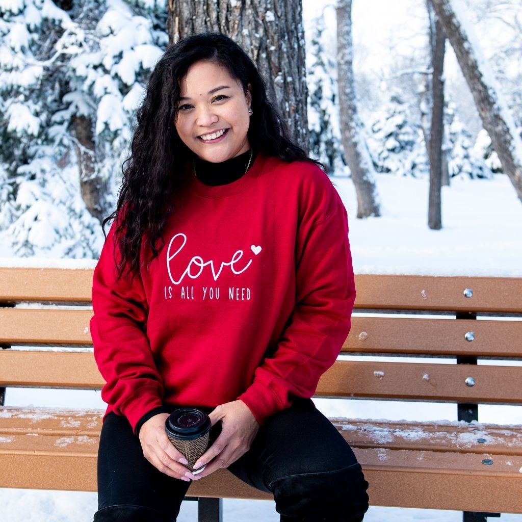 Female wearing red sweatshirt embroidered with Love is all you need - DSY Lifestyle