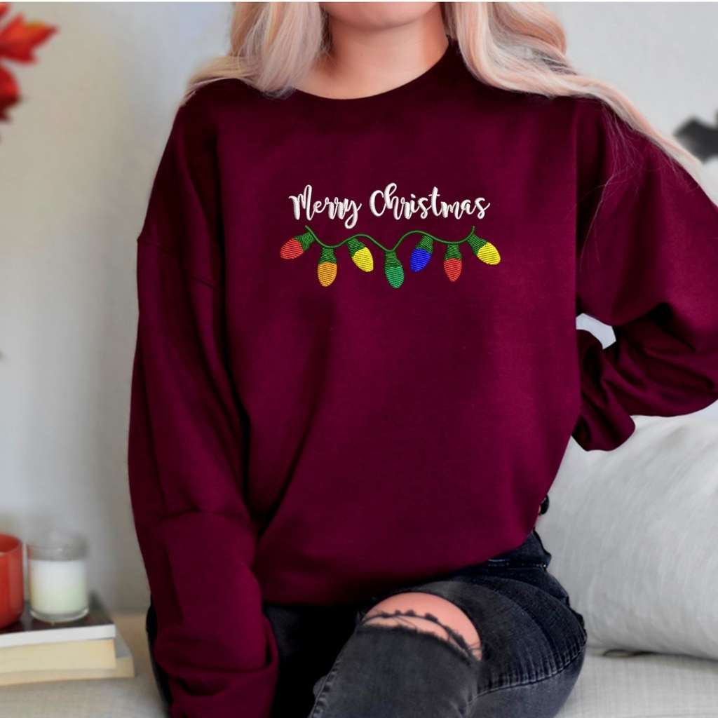 Female wearing a burgundy crewneck sweatshirt embroidered with Merry Christmas in the front- DSY Lifestyle